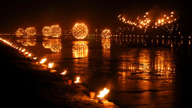 Thousands of carefully controlled flames reflect off the water.