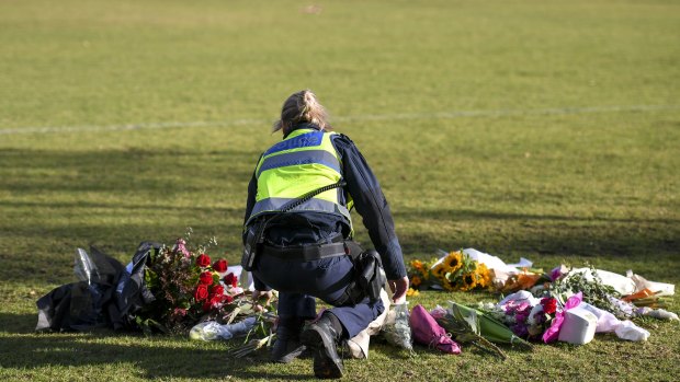 A female police officer lay flowers at the scene where Eurydice Dixon's body was found.