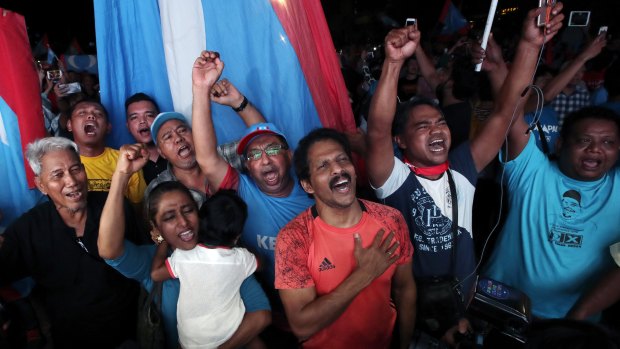 Opposition party supporters cheer and wave their party flags on election night.
