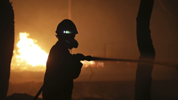 A firefighter sprays water on the fire in the town of Mati, east of Athens.