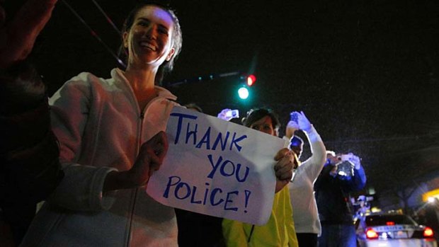 Members of the public cheer as police officers leave the scene where Dzhokhar Tsarnaev.