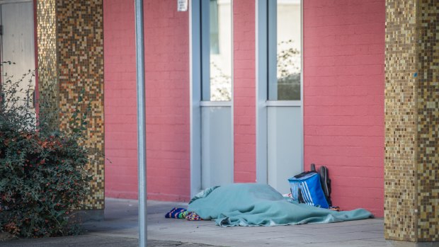 A homeless person sleeps rough outside the ACT Legislative Assembly.