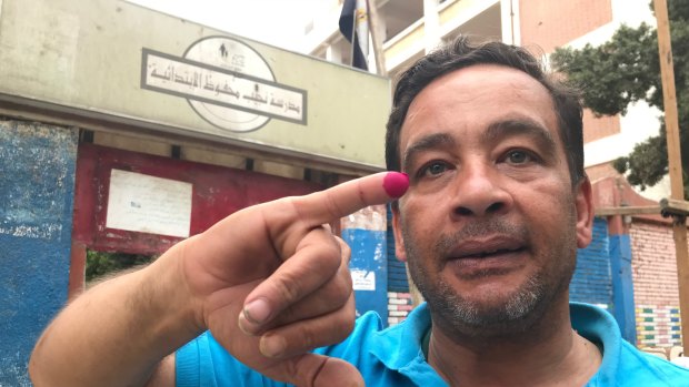 Emad Rashad shows off his inked finger as proof of voting.