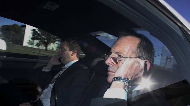 Prime Minister Tony Abbott on the phone in his Holden Caprice C1 on returning to RAAF Fairbairn in Canberra from attending the Nelson Mandela memorial. Photo: Andrew Meares