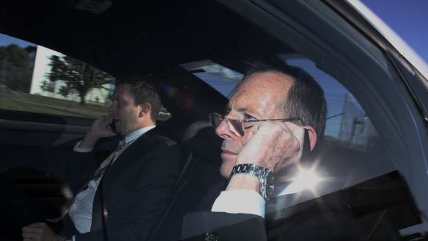 Prime Minister Tony Abbott on the phone in his Holden Caprice C1 on returning to RAAF Fairbairn in Canberra from attending the Nelson Mandela memorial. Photo: Andrew Meares