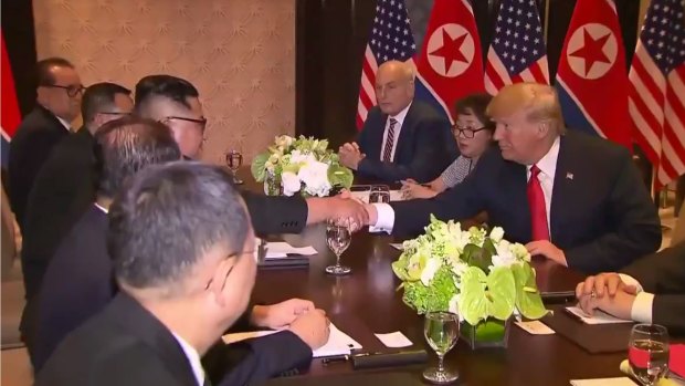 Trump and Kim shake hands with their advisers by their sides.