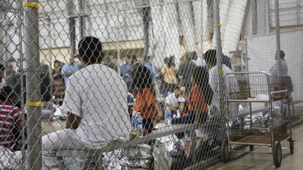 People taken into custody related to cases of illegal entry into the United States, sit in one of the cages at a facility in McAllen, Texas.