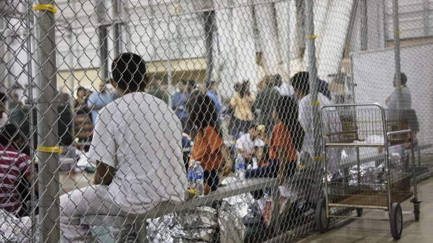 People taken into custody related to cases of illegal entry into the United States, sit in one of the cages at a facility in McAllen, Texas.