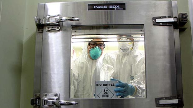Health personnel hold a container with H7N9 viral specimens from China at the National Influenza Centre in Taiwan.
