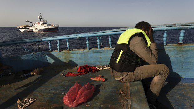 A refugee sits in despair on a wooden fishing boat as he waits to be rescued off the coast of Libya. 