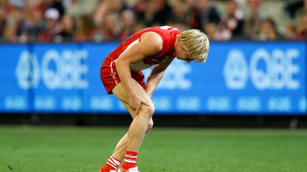 Isaac Heeney of the Swans holds his knee as he sustains an injury during Saturday night's game.