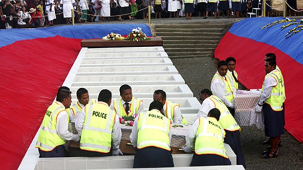 Pallbearers lower a casket into the mass burial site at Apia as Samoa marked a national day of mourning for tsunami victims.