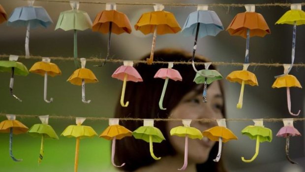 A woman poses for a photo with the paper fold umbrellas at the occupied area in Causeway Bay.