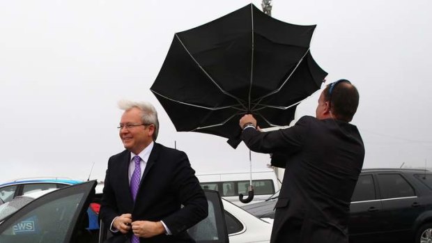 Prime Minister Kevin Rudd is assisted by a member of his protection team in wet and blustery conditions at the Hobart showgrounds on Saturday August 10.