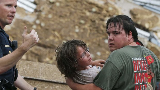 A child is carried from the rubble of the Plaza Towers Elementary School following the tornado in Moore, Oklahoma.