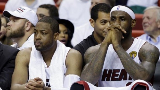 Miami Heat forward LeBron James, right and guard Dwyane Wade sit on the bench.