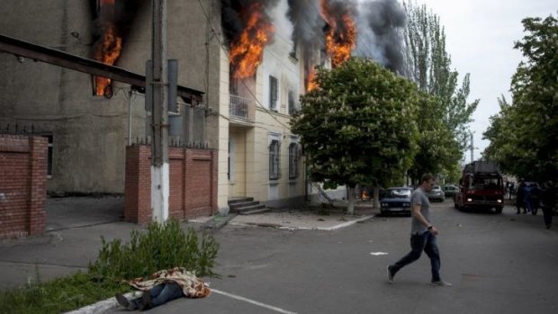 The body of a police officer, left, lies outside a police station that burns in Mariupol, eastern Ukraine. A clash between government forces and pro-Russian forces there has left over 20 dead.