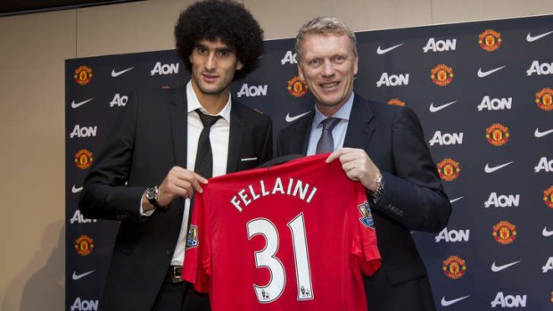Pressure: Marouane Fellaini shows off his Manchester United shirt with manager David Moyes.
