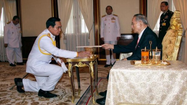 Coup leader General Prayut Chan-O-Cha recieves the interim constitution from King Bhumibol Adulyadej.