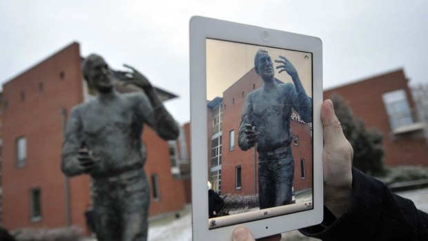 A visitor takes a picture of the statue with an iPad.