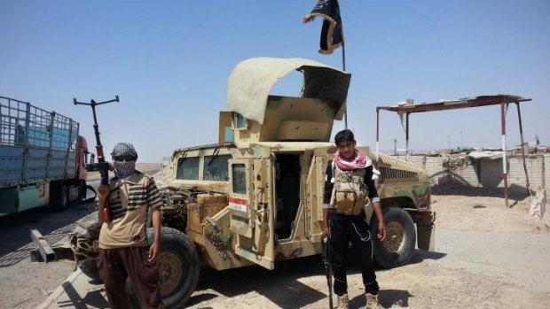 Underestimated: Islamic State group militants stand with a captured Iraqi Army Humvee.