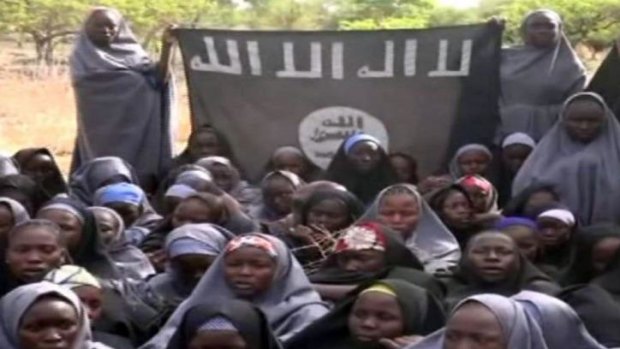 Girls in the video hold a flag saying "There is no god, but Allah".