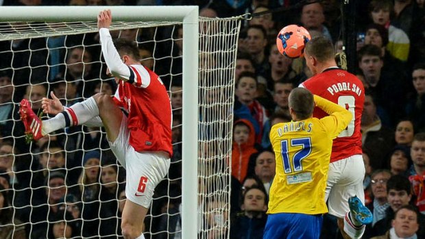 Double strike: Arsenal's Lukas Podolski heads home his second goal to help his side advance in the FA Cup.