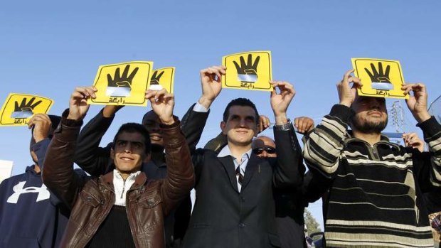 People shield their faces with specially-constructed cards showing the four-finger symbol of Rabaa, to show their support for ousted Egyptian President Mohamed Mursi, as they observe a solar eclipse in Amman, Jordan.