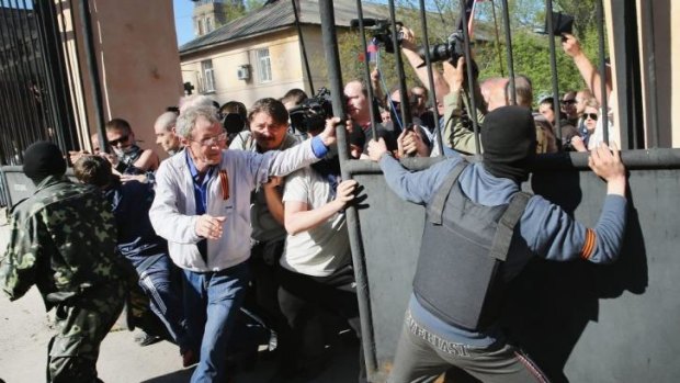 Pro-Russian activists break through the gate in front of the television station in Donetsk.