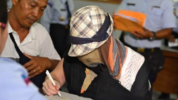 Schapelle Corby signs paperwork at the Corrections Bureau.