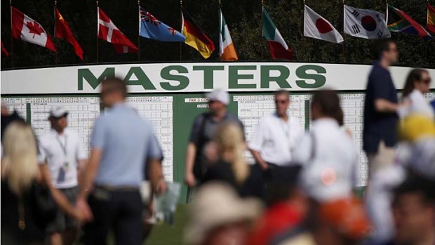 Spectators walk past the main scoreboard during a practice round in preparation for the 2013 Masters golf tournament at the Augusta National Golf Club.