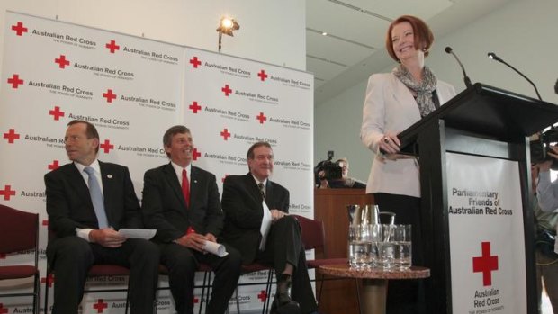 Tony Abbott fails to see the funny side as Julia Gillard cracks a joke during the Red Cross morning tea at Parliament House in Canberra.