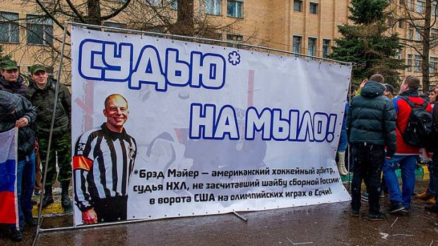 Demonstrators holding a banner with a photo of American referee Brad Meier and a message reading "Turn the referee into soap?.
