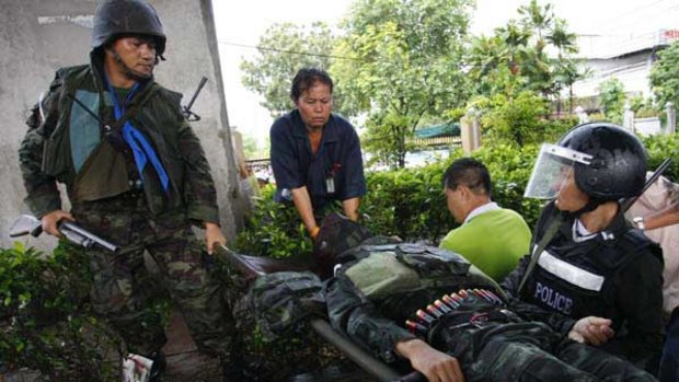 Fatal hit ... Soldiers carry away a comrade after he was shot in the head during a clash with anti-government protesters in Bangkok. He later died.