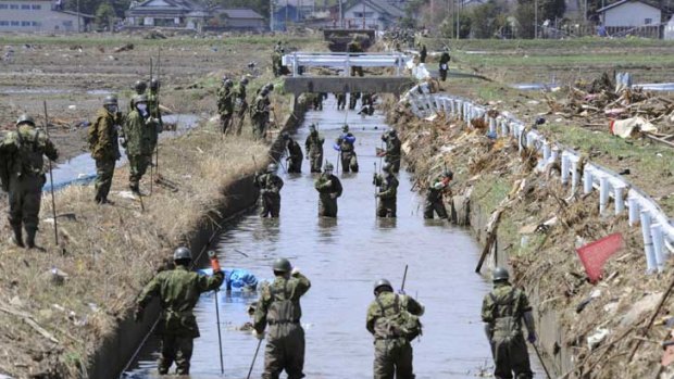 Japanese soldiers search a stream for bodies at Minami Soma, in north-east Japan.