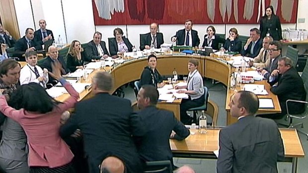 Wendi Deng lunges towards a man trying to attack her husband, News Corp Chief Executive and Chairman Rupert Murdoch, during a parliamentary committee hearing on phone hacking.