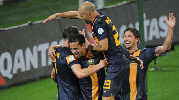 Alex Brosque is mobbed by Socceroo teammates.