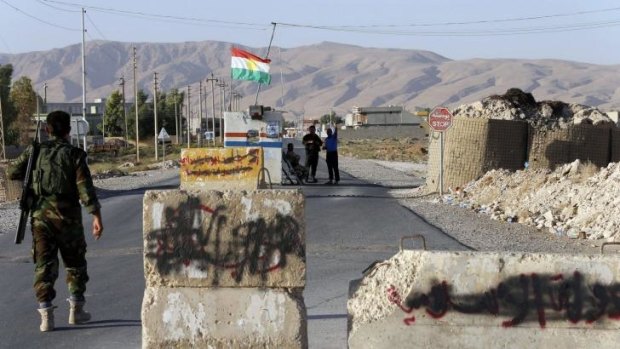 Contested zone: Kurdish Peshmerga fighters man a checkpoint in Makhmour, south of Erbil. Words written on stone slabs by the Islamic State were painted out after it was retaken from them.