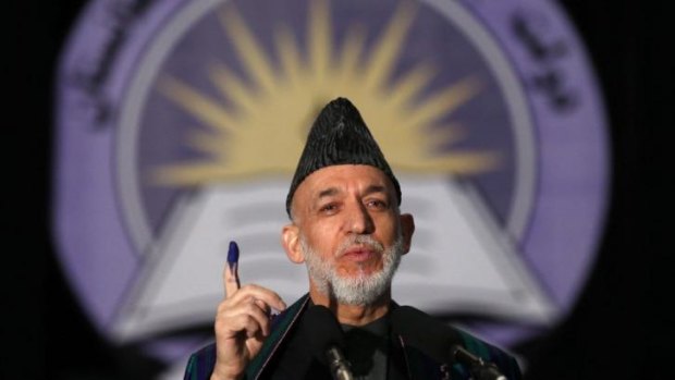 Afghan President Hamid Karzai holds up his inked stained finger after voting.