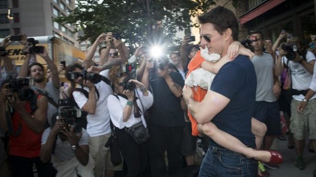 Tom Cruise carries Suri past a group of paparazzi outside his New York apartment.