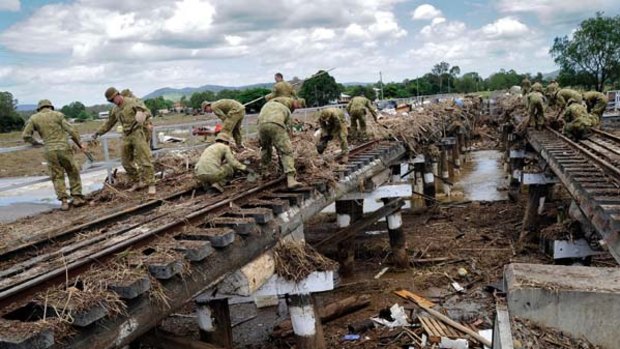 Dirty work ... soldiers from the Emergency Support Force Group help clear the railway line across Sandy Creek at Grantham.