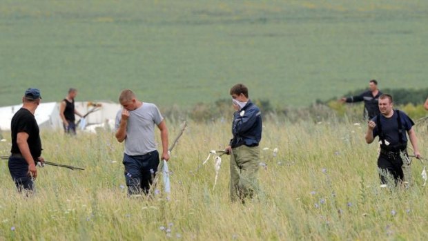 Men search a field in eastern Ukraine for victims of flight MH17.