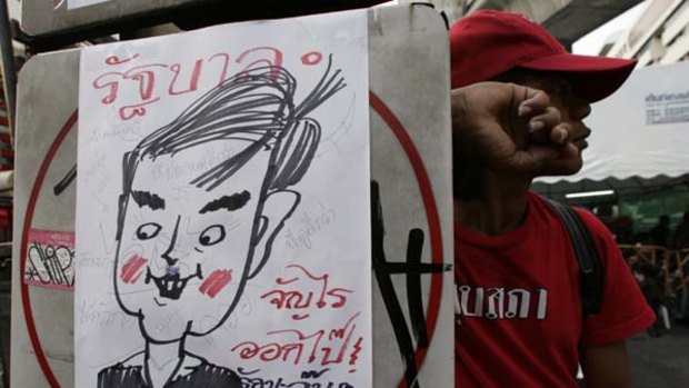 Had enough … a Red Shirt protester stands next to a drawing denouncing the Thai Prime Minister, Abhisit Vejjajiva, during a rally in Bangkok.