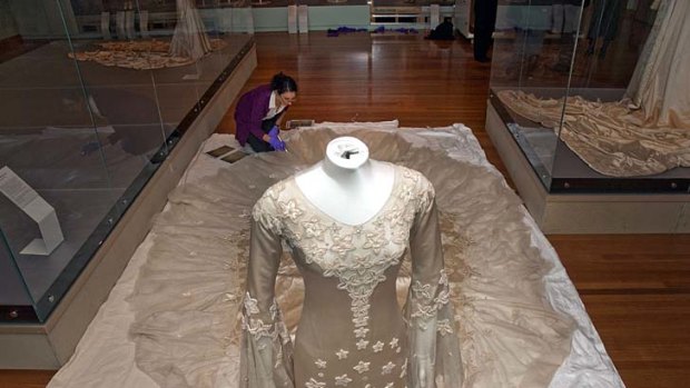 Romantic ... specialist textile installer Keira Millar from the Victorian and Albert Museum inspects the dress by designer and royal couturier Norman Hartnell.