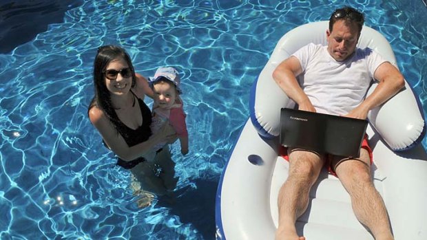 Tweeting by the pool: Ben Neumann checks his emails as wife Martine and daughter Ella enjoy the water.