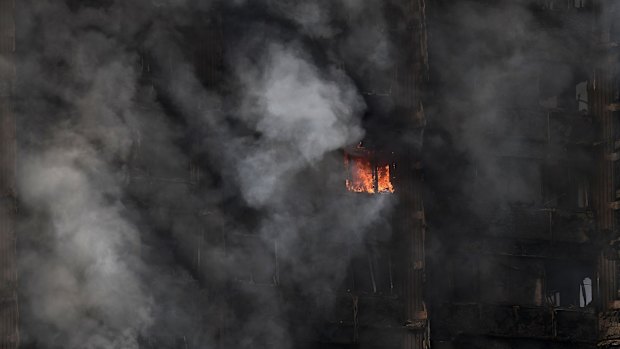 A fire still burns and smoke rises from the building after dawn on Wednesday.