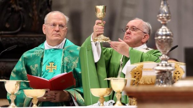 Consecrating the wine: Pope Francis, right, supported by the Archbishop of Budapest, Peter Erdo, celebrates the opening Mass of the synod of bishops in St Peter's Basilica in Vatican City.