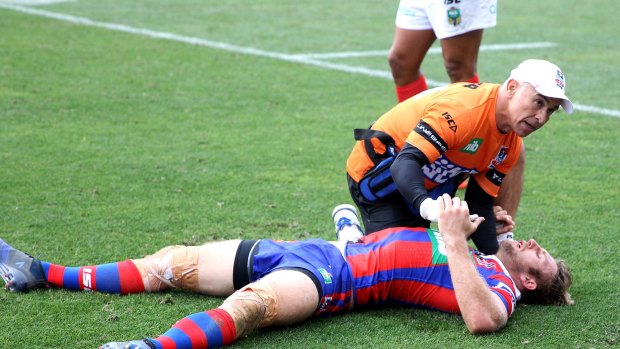 Down: Brendan Elliot of the Knights is treated by Tony Ayoub after being felled during Newcastle's clash with South Sydney.