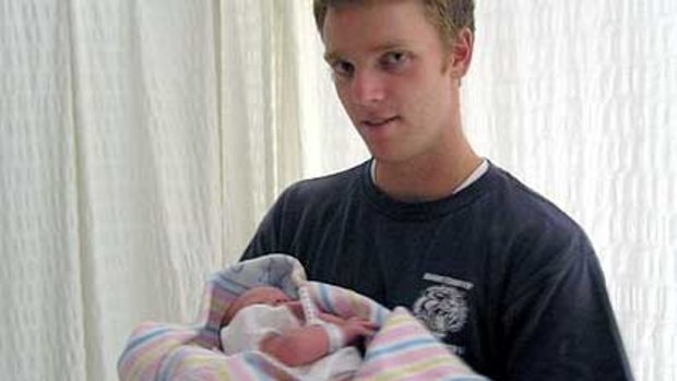 Corporal Mathew Hopkins holding his newborn child. He died after being wounded while on combat patrol near the town of Kakarak in Afghanistan.
