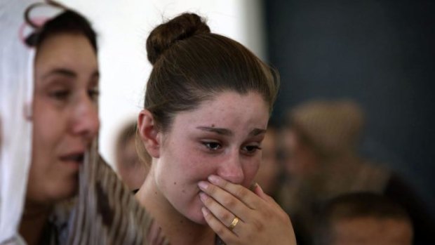 An Iraqi Yazidi woman who fled Sinjar, cries as she stands among others at a school where they are taking shelter.